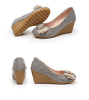 A pair of women's wedge pumps shown from multiple angles on a white background. The shoes feature a textured gray and silver glitter upper with a beige bow and jeweled embellishment on the toe, a tan wedge heel, and a light pink interior, Obroi