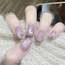 Nails with purple floral design on a textured surface, Obroi