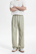 Person wearing light green wide-leg pants and a white top on a white background, Obroi