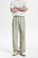 Person wearing light green wide-leg pants and a white top on a white background, Obroi
