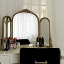 Makeup vanity with gold-framed mirrors and various items on a white background, Obroi