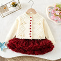 A toddler girl's two-piece knit outfit set, featuring a cream-colored cardigan sweater with red buttons and a matching deep red ruffled tutu skirt, displayed on a wooden hanger against a textured white background, Obroi