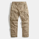 A pair of khaki cargo pants laid flat against a light gray background, featuring multiple utility pockets and a button closure, Obroi
