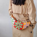Person wearing a colorful crochet bag over their shoulder against a plain background, Obroi