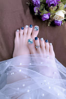 Close-up of toes with decorative nail art and rings, wearing a white sheer fabric, Obroi