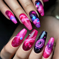 Nails with galaxy design in pink, purple, and blue on a hand, Obroi