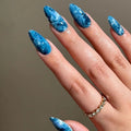 Hand with blue marbled nail polish on a neutral background, Obroi