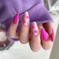 Obroi Close-up of a hand with pink and heart-patterned nails wearing a purple sleeve.