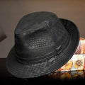 Black fedora hat on a reflective surface with a colorful box in the background, Obroi