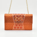 Orange clutch bag with intricate patterns and a chain strap on a white background, Obroi