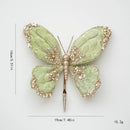 Decorative butterfly hairpin with green wings and gold accents on a white background, Obroi