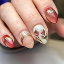 Obroi Close-up of a hand with intricately designed nails featuring floral patterns and gold accents.