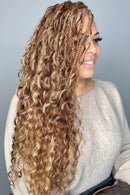 Woman with long, wavy hair smiling indoors, Obroi