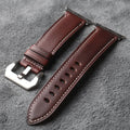 Brown leather watch strap with silver buckle on a gray textured background, Obroi