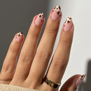 Obroi Hand with pink nails and brown cow print design on a neutral background