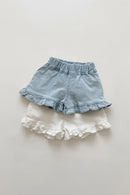 Pair of denim shorts with ruffled hem on a light background, Obroi