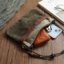 Brown leather pouch with a phone inside on a wooden surface, Obroi