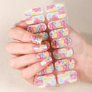Nail art stickers with colorful tropical design held by a hand on a beige background, Obroi