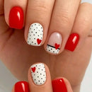 Nails with red and white polka dot design featuring hearts on a neutral background, Obroi