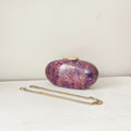 Purple and gold handbag on a white surface with a plain background