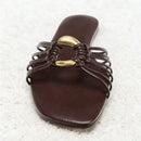 Brown sandal with braided design and gold buckle on a textured white surface, Obroi