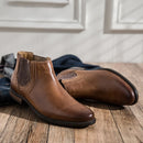 Brown leather Chelsea boots on a wooden floor with jeans in the background ,Obroi
