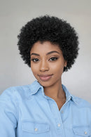 Woman with short, curly black hair wearing a light blue shirt against a gray background, Obroi