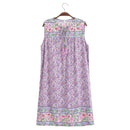 A sleeveless lavender floral nightgown dress with embroidered floral borders and a tassel tie at the neckline, hanging on a wooden hanger against a white background, Obroi
