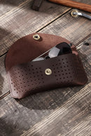Brown leather case with sunglasses on a wooden surface, Obroi