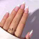 Hand with pink and white nail polish wearing a gold ring on a light background, Obroi