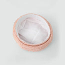 A round, low-profile bucket hat in a light pink tweed fabric with a white fabric lining, photographed from a top-down perspective on a light gray background, Obroi
