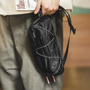 Person holding a black mesh bag with white stitching, blurred background, Obroi