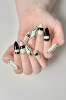 Hand with black and white nail art on a neutral background, Obroi