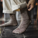 Person wearing brown textured socks on a dark stone floor, Obroi