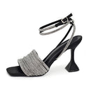 Black high-heeled shoe with silver embellishments on a white background, Obroi
