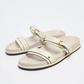 Pair of white sandals with gold buckles on a light gray background, Obroi