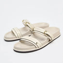 Pair of white sandals with gold buckles on a light gray background, Obroi