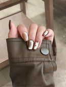 Close-up of a hand with metallic nail polish on a blurred background, Obroi