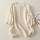 Beige linen shirt on a light beige surface with a magazine in the background, Obroi