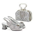 Silver high-heeled shoes and matching clutch with crystal embellishments on a white background, Obroi