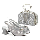 Silver high-heeled shoes and matching clutch with crystal embellishments on a white background, Obroi