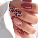 Obroi Hand with maroon and black leopard print nail design on a blurred background