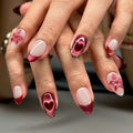 Close-up of a hand with red and pink floral nail art on a neutral background, Obroi
