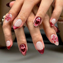 Close-up of a hand with red and pink floral nail art on a neutral background, Obroi