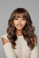 Woman with long wavy brown hair and bangs against a gray background, Obroi