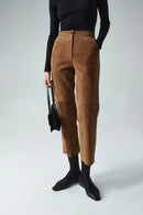 Person wearing brown pants and black top with a white background, Obroi