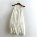 White lace dress on a wooden hanger against a white wall, Obroi