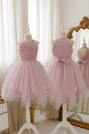 A light pink formal dress displayed on a mannequin, shown from both the front and back. The sleeveless dress features a textured rose-pattern bodice on the front, a high neck, and a layered tulle skirt with a bow at the back waist, Obroi