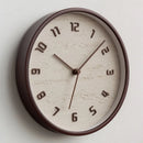 Round wall clock with brown frame and beige face on a light gray background, Obroi