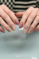 Close-up of hands with pink nail polish and floral designs on a blurred background, Obroi